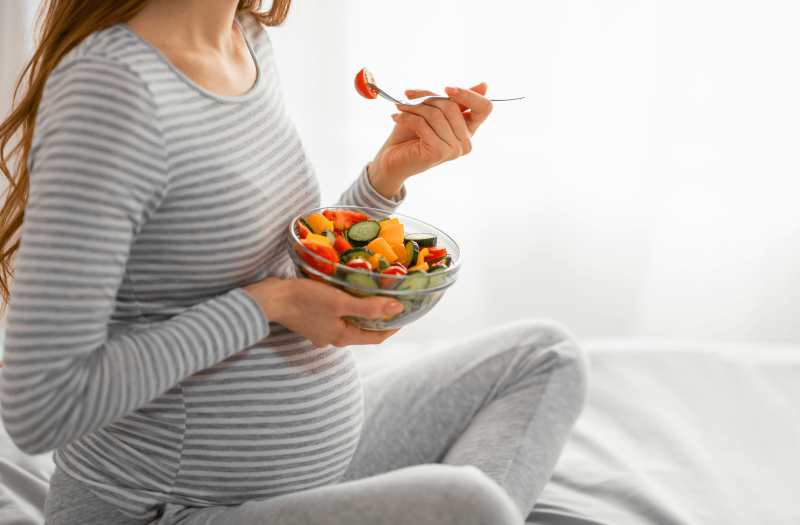 kismama a kanapén, aki a terhességi cukorbetegség étrend részeként kis tál salátát eszik